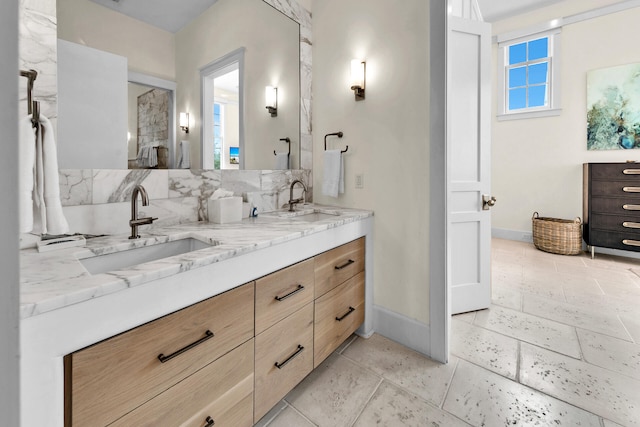 full bath with a sink, baseboards, and double vanity