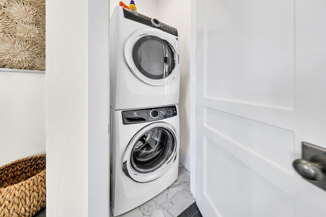 laundry room with marble finish floor, laundry area, and stacked washer / dryer