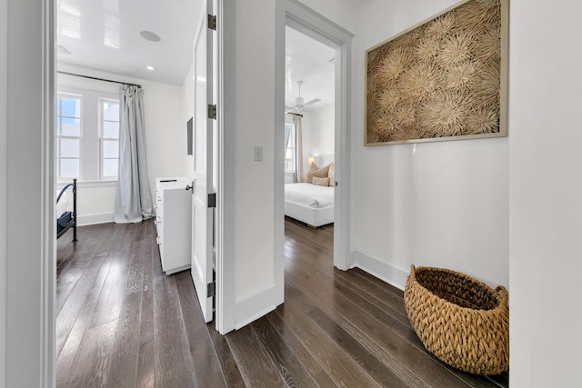 corridor with baseboards and dark wood-type flooring