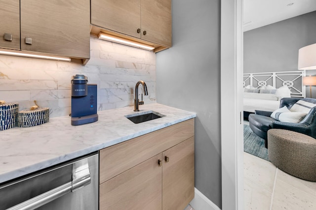 kitchen with light stone countertops, baseboards, backsplash, and a sink