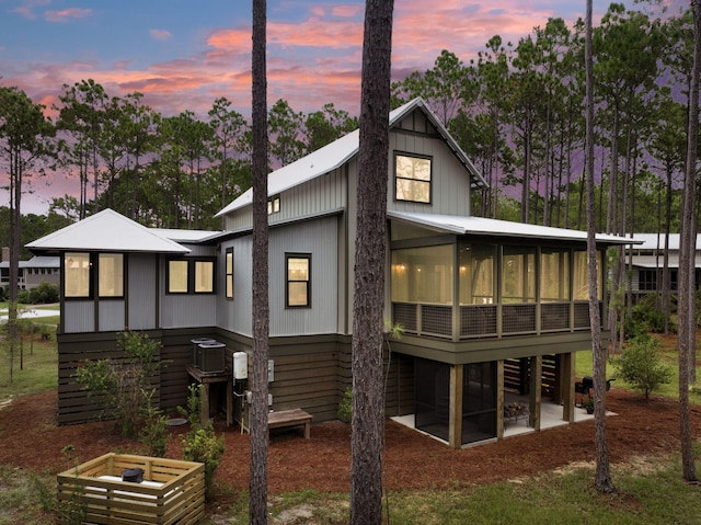 back house at dusk with a sunroom