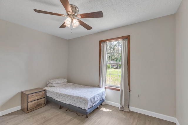 bedroom featuring ceiling fan, light wood-type flooring, and a textured ceiling