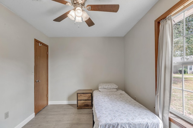 bedroom featuring multiple windows, light hardwood / wood-style flooring, and ceiling fan