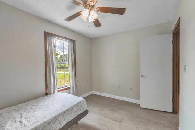 bedroom featuring a textured ceiling, light wood-type flooring, and ceiling fan