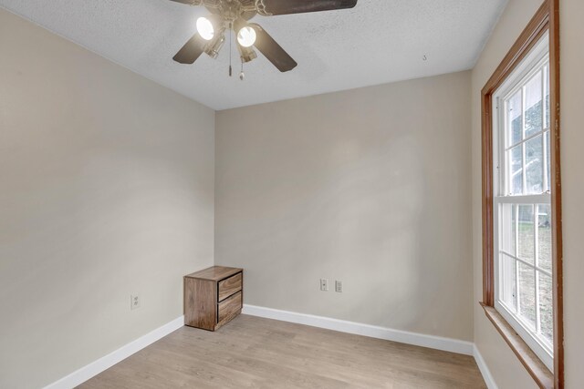 spare room with ceiling fan, light hardwood / wood-style floors, a textured ceiling, and a wealth of natural light