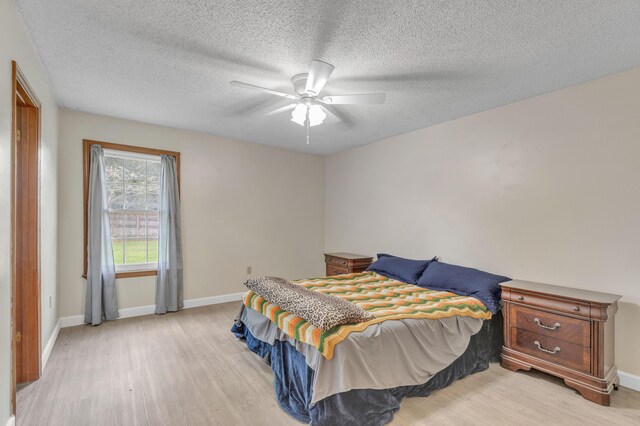 bedroom with a textured ceiling, light wood-type flooring, and ceiling fan