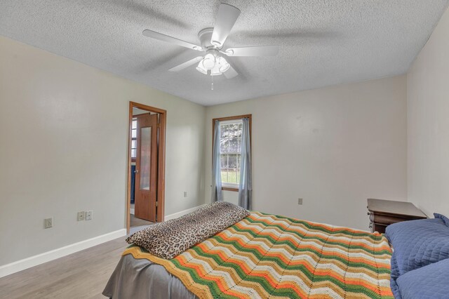 bedroom featuring ceiling fan, light hardwood / wood-style floors, and a textured ceiling