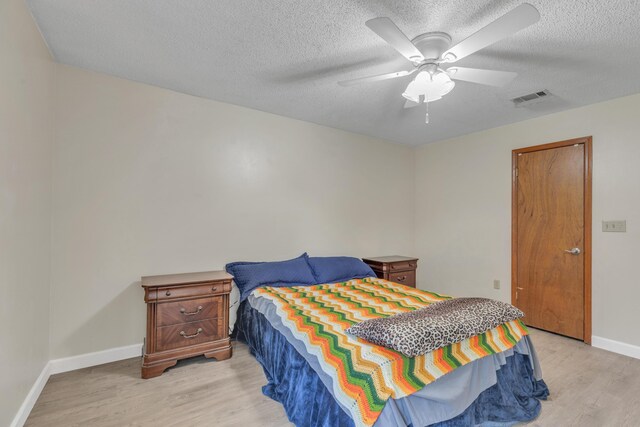 bedroom featuring ceiling fan, light wood-type flooring, and a textured ceiling