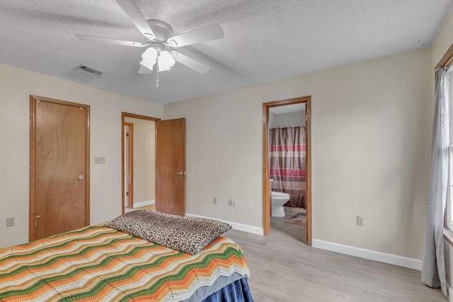 bedroom with ensuite bathroom, ceiling fan, light hardwood / wood-style floors, and a textured ceiling