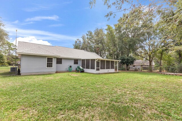 rear view of house featuring a sunroom and a lawn