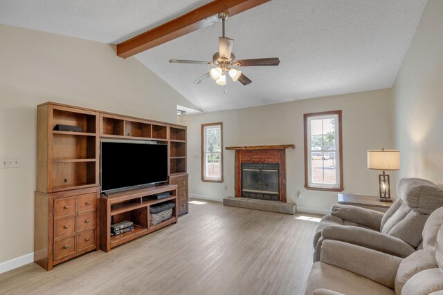 living room featuring a fireplace, lofted ceiling with beams, plenty of natural light, and light hardwood / wood-style floors