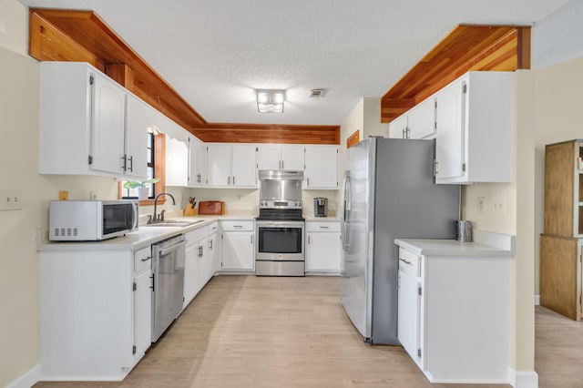 kitchen with white cabinets, sink, light hardwood / wood-style flooring, a textured ceiling, and appliances with stainless steel finishes