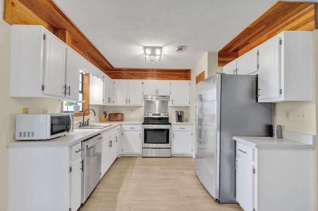 kitchen featuring sink, light hardwood / wood-style floors, a textured ceiling, white cabinets, and appliances with stainless steel finishes