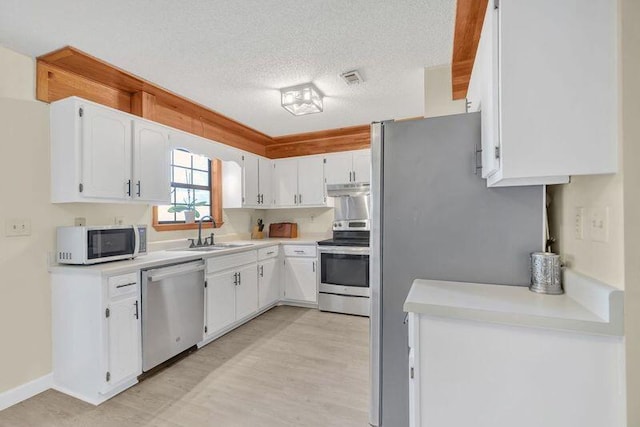 kitchen featuring sink, light hardwood / wood-style flooring, a textured ceiling, white cabinets, and appliances with stainless steel finishes