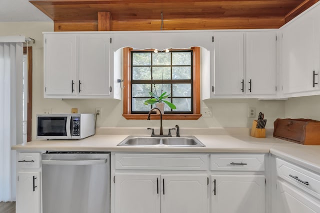 kitchen featuring stainless steel dishwasher, white cabinets, and sink