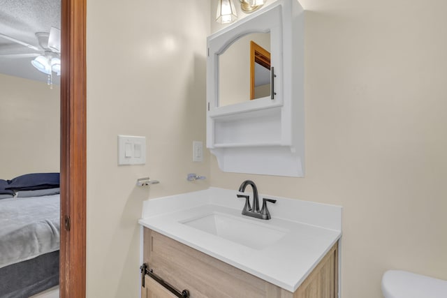 bathroom featuring ceiling fan, vanity, a textured ceiling, and toilet