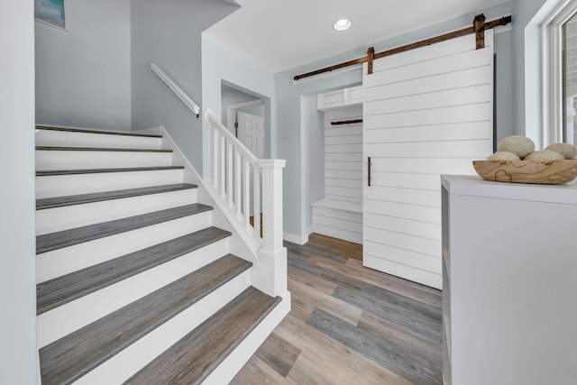 staircase featuring a barn door and hardwood / wood-style floors