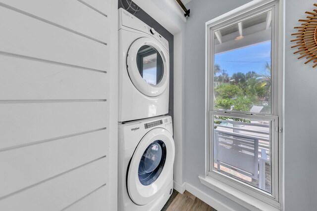 laundry area featuring a barn door, wood-type flooring, and stacked washer and dryer