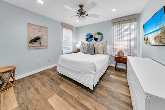 bedroom featuring ceiling fan, hardwood / wood-style floors, and multiple windows