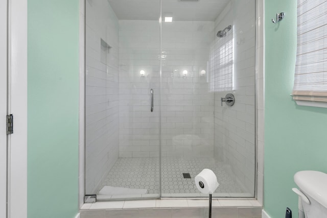 bathroom featuring toilet and a shower with door