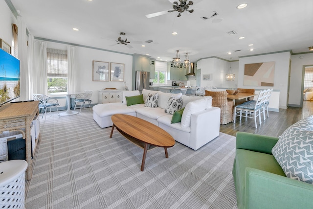 living room featuring ceiling fan with notable chandelier, plenty of natural light, and crown molding