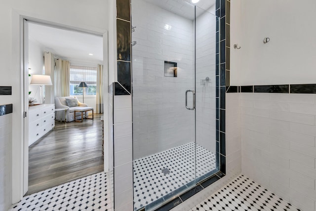 bathroom with tile walls, wood-type flooring, and an enclosed shower