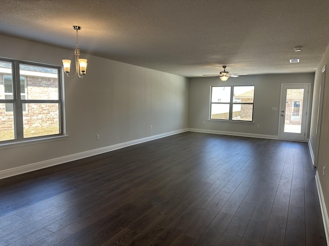 empty room with dark hardwood / wood-style floors, ceiling fan with notable chandelier, and a textured ceiling