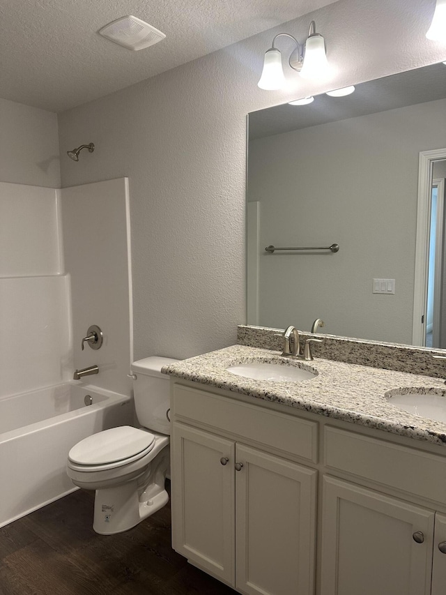 full bathroom with hardwood / wood-style flooring, shower / bathtub combination, toilet, and a textured ceiling