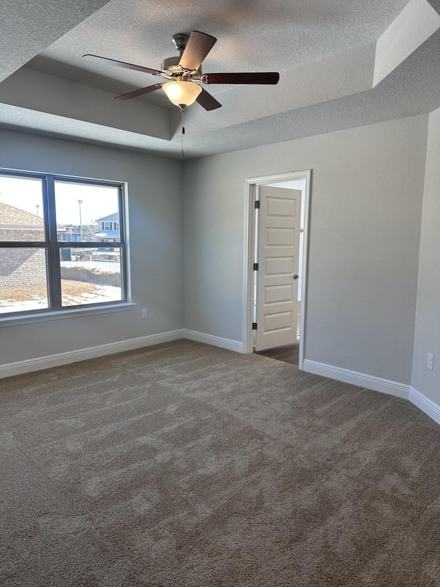 carpeted spare room featuring ceiling fan, a textured ceiling, and a tray ceiling