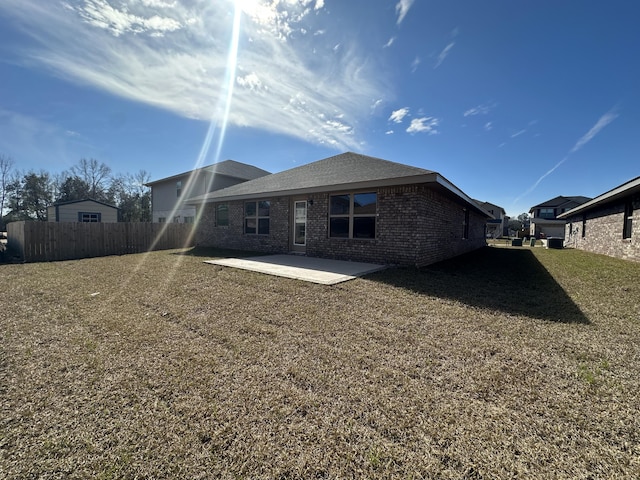 rear view of house featuring a yard, brick siding, a patio, and fence