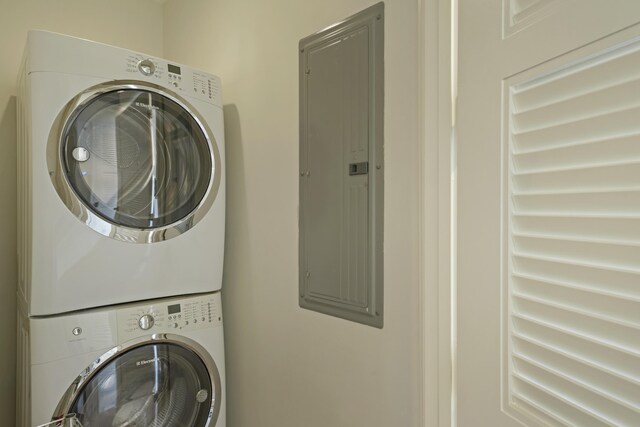 laundry area featuring stacked washer / drying machine and electric panel