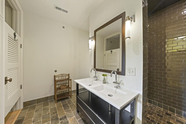 bathroom featuring tile patterned flooring, vanity, and tiled shower