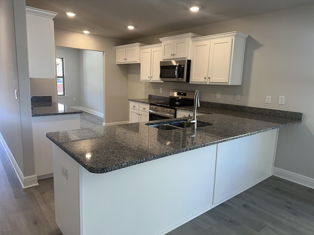 kitchen featuring appliances with stainless steel finishes, dark wood-style flooring, white cabinets, and a peninsula