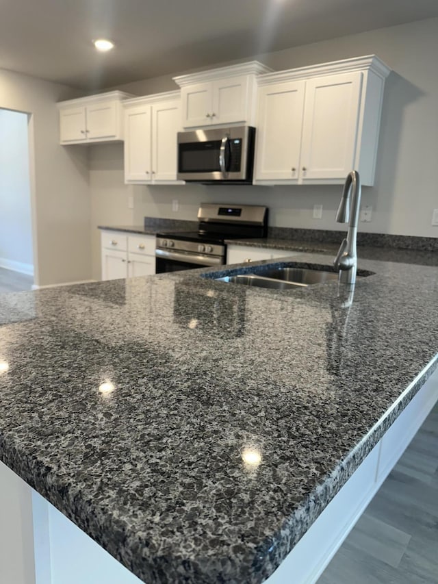 kitchen with appliances with stainless steel finishes, white cabinets, a sink, and a peninsula