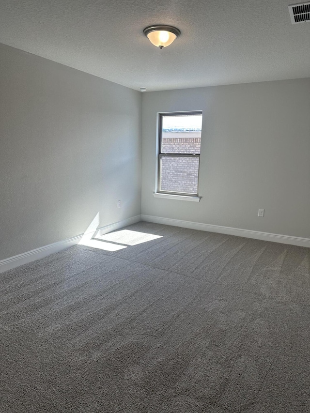 carpeted spare room featuring visible vents, a textured ceiling, and baseboards