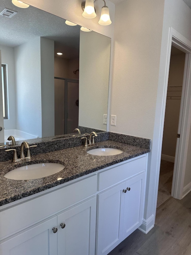 full bath with a shower stall, a spacious closet, a sink, and wood finished floors