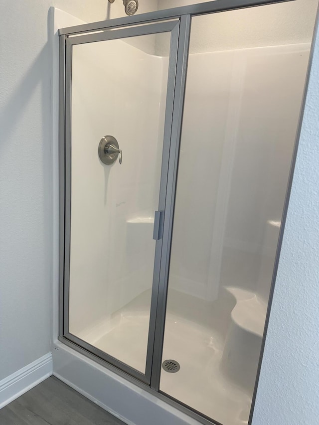 bathroom featuring a shower stall, baseboards, and wood finished floors