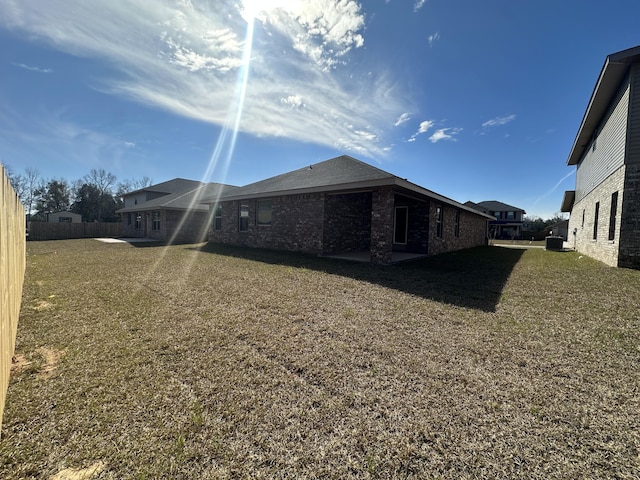 view of side of property with a yard, brick siding, and fence