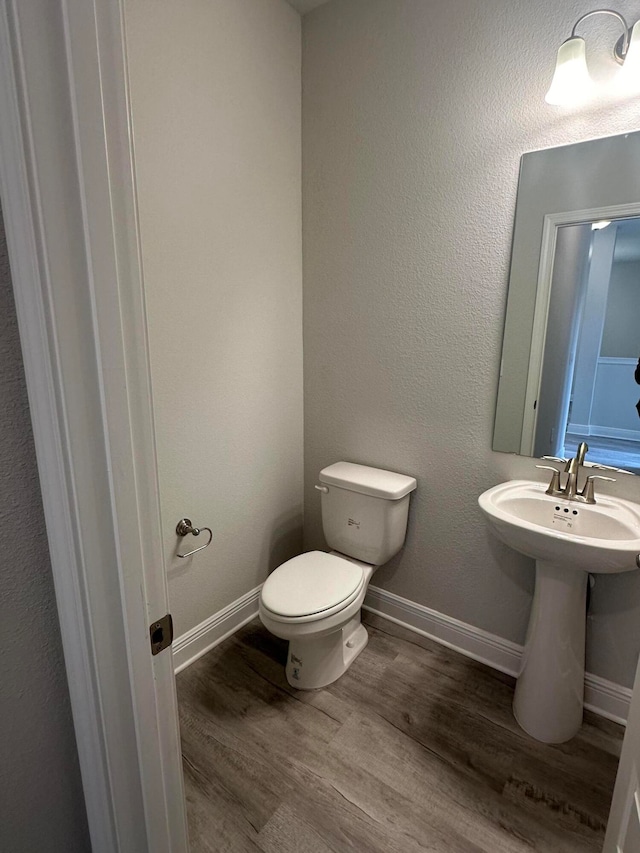 bathroom with toilet and wood-type flooring