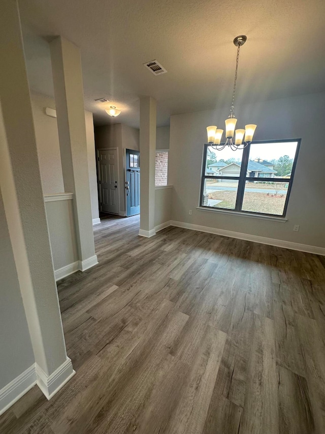 empty room featuring wood-type flooring and a chandelier