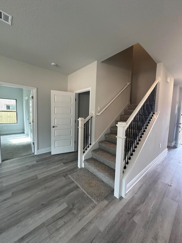 stairs featuring a textured ceiling and hardwood / wood-style floors