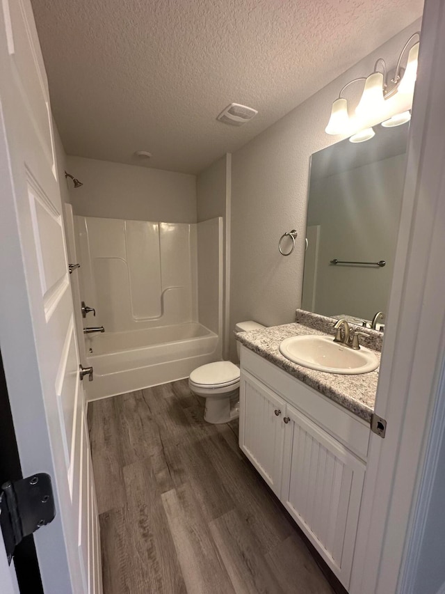 full bathroom with hardwood / wood-style flooring, washtub / shower combination, vanity, and toilet