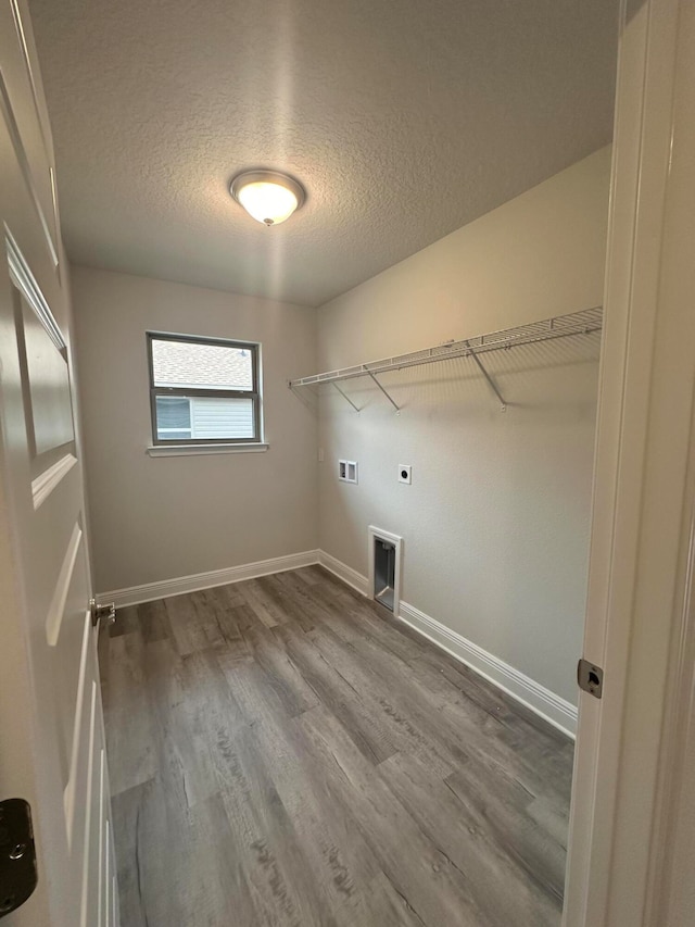 clothes washing area featuring hardwood / wood-style floors, hookup for a washing machine, electric dryer hookup, and a textured ceiling