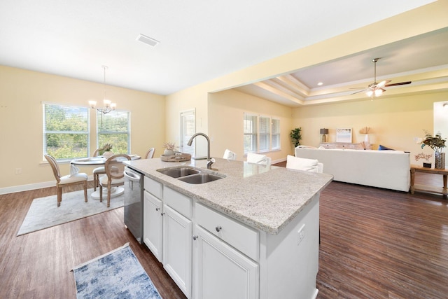 kitchen featuring sink, dark wood-type flooring, an island with sink, and a tray ceiling