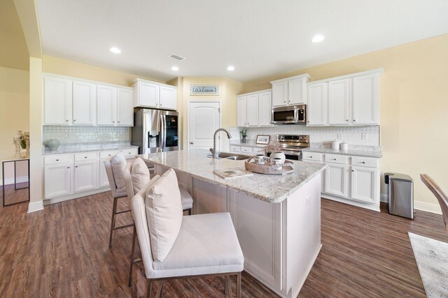 kitchen featuring backsplash, dark hardwood / wood-style floors, a kitchen island with sink, sink, and stainless steel appliances