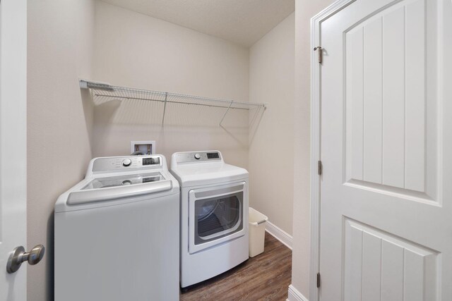 washroom with dark hardwood / wood-style floors and washing machine and clothes dryer