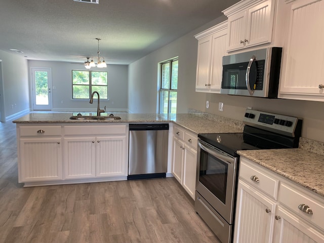 kitchen with sink, appliances with stainless steel finishes, light hardwood / wood-style floors, a healthy amount of sunlight, and kitchen peninsula