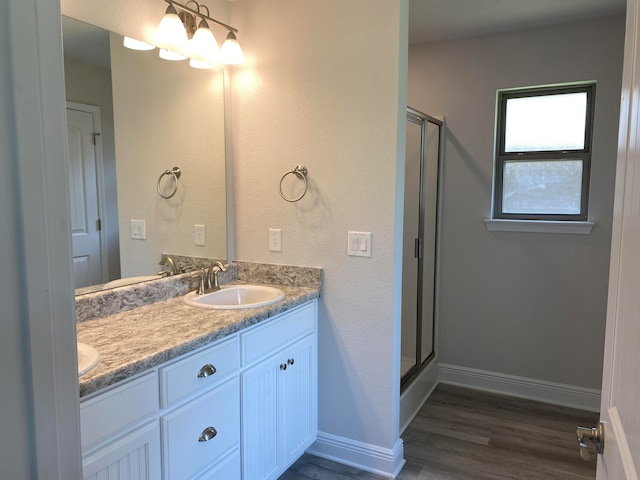 bathroom with an enclosed shower, double vanity, and hardwood / wood-style floors