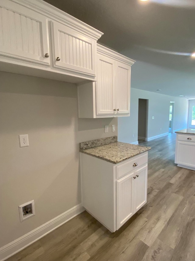 interior space with white cabinetry, hardwood / wood-style flooring, and light stone countertops