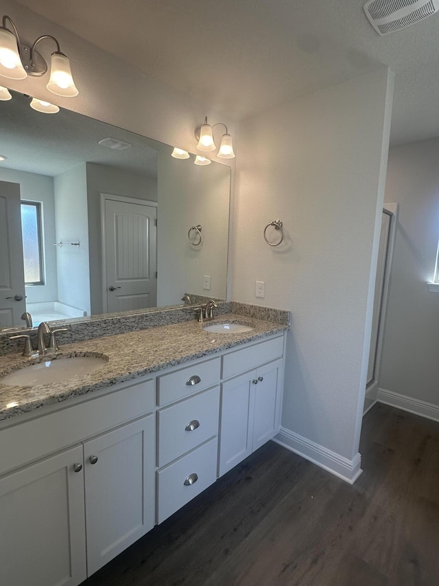 full bath featuring visible vents, a sink, and wood finished floors